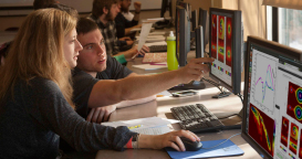 Photo of two students looking at a computer